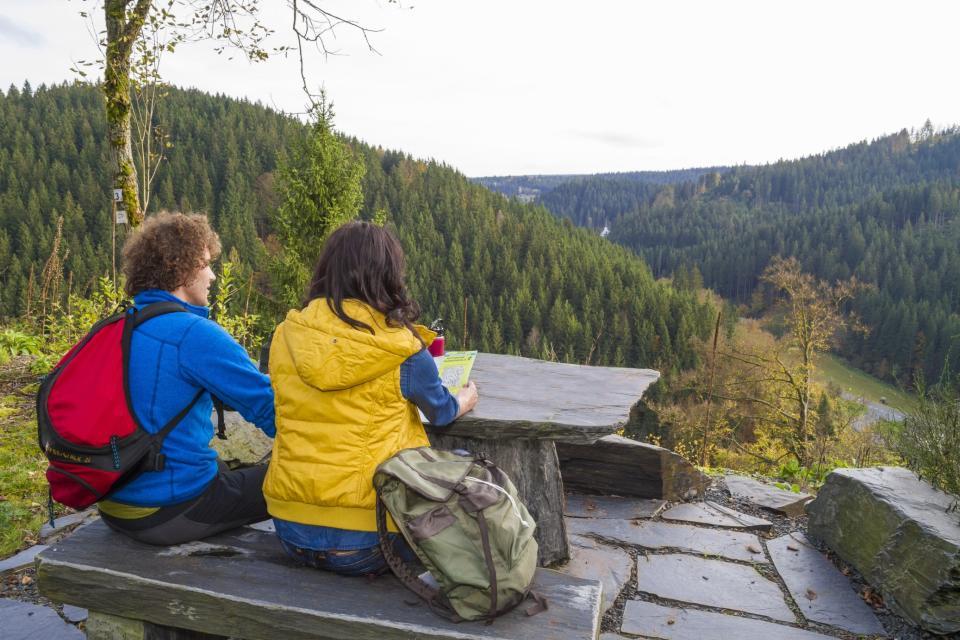 2 Menschen sitzen vor einer Aussicht am Berg